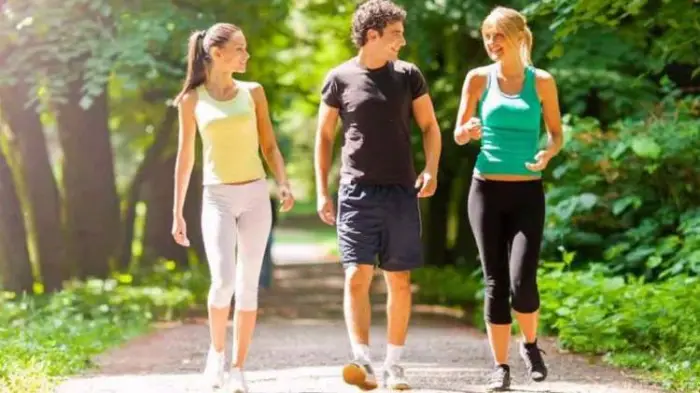 Due ragazze e un ragazzo che passeggiano nel verde per tenersi in forma