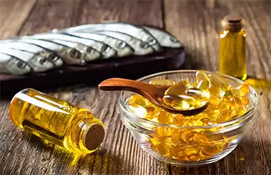 sardine allineate su un tagliere e vari integratori di Omega 3 sia in capsule che liquido