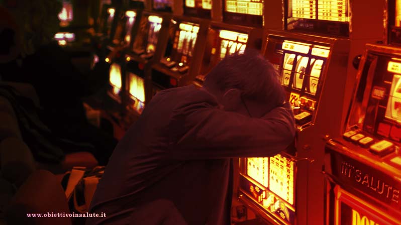 Uomo disperato appoggia la testa su uno slot machine in un casinò