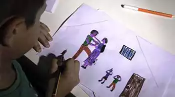 Un bambino disegna su un foglio una scena familiare in cui i genitori litigano e due bimbi si tappano le orecchie