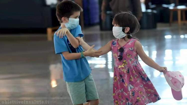 Un bambino e una bambina con la mascherina giocano 
