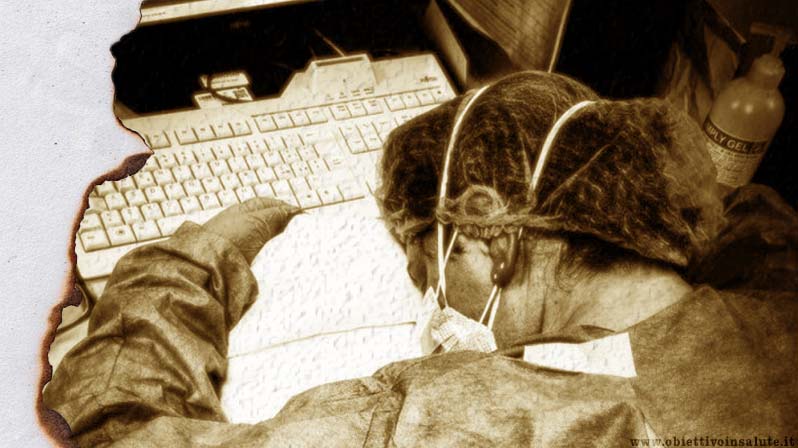 Covid, nemico pubblico n.1. Un'infermiera addormentata sulla tastiera del Pc con ancora addosso il camice e la mascherina