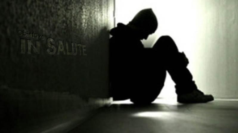 Immagine in bianco e nero che rappresenta un ragazzo afflitto di tossicodipendenza che si trova rannicchiato a terra in penombra