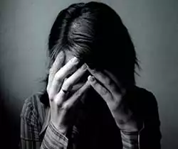 Foto in bianco e nero con una donna tossicodipendente con le mani sul proprio volto