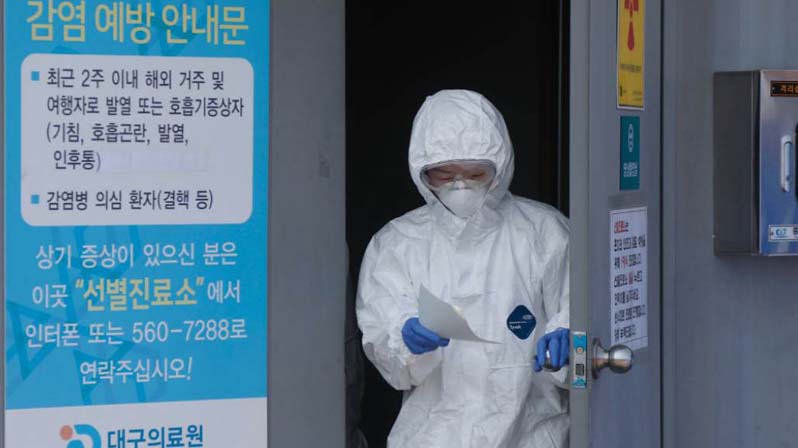 Medico coreano con protezioni anti covid esce da una stanza con un documento in mano