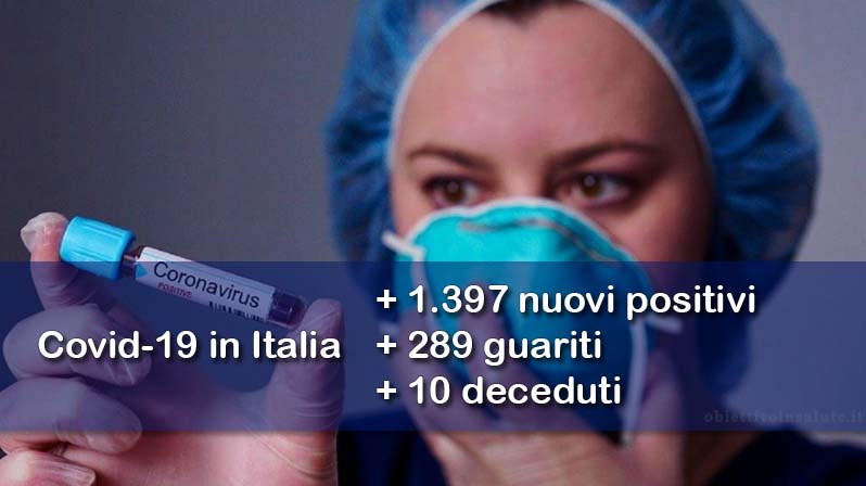 Un'infermiera tiene tra le dita una privetta con del sangue con su scritto "Coronavirus positivo". in primo piano dell’immagine vengono riportati i dati aggiornati del contagio in Italia
