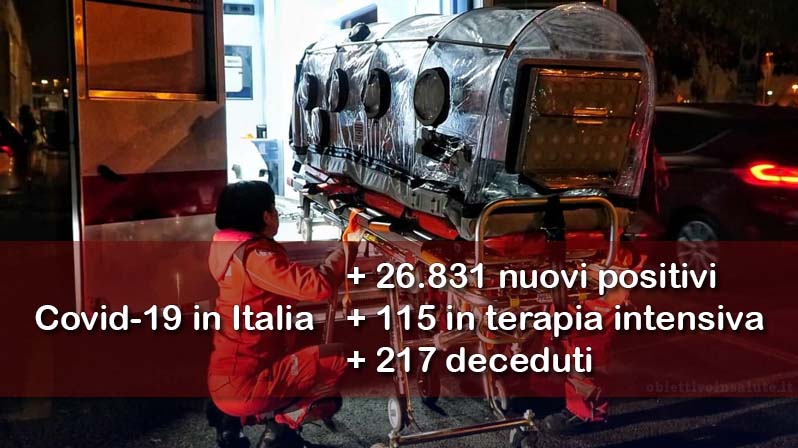Due infermieri mettono una barella speciale per il contenimento del virus in una ambulanza, in primo piano dell’immagine vengono riportati i dati aggiornati del contagio in Italia