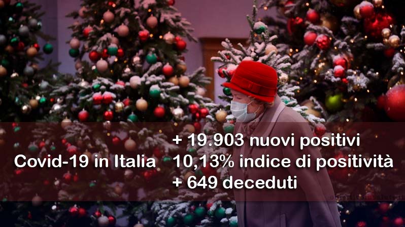 Un'anziana signora passeggia per strada con la mascherina con sullo sfondo tanti alberi di natali addobbati, in primo piano dell’immagine vengono riportati i dati aggiornati del contagio in Italia