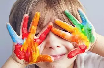 Un bambino con le mani colorate davanti agli occhi