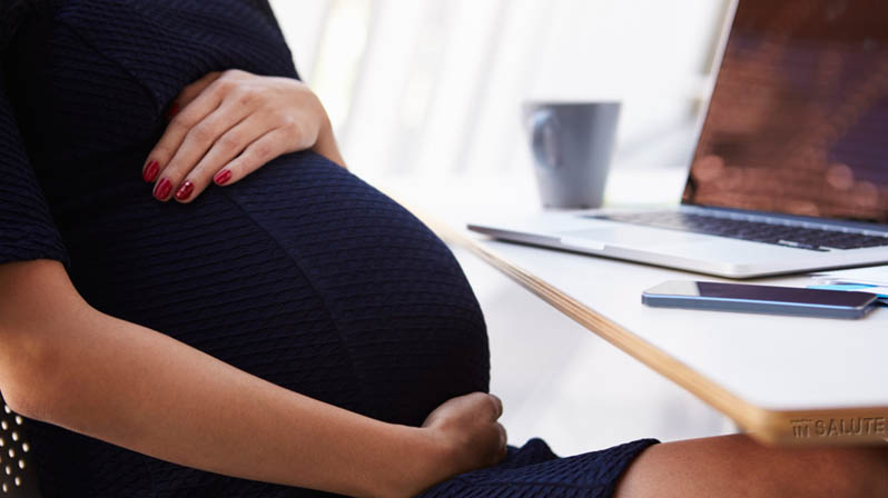 Donna incinta seduta alla scrivania per lavoro